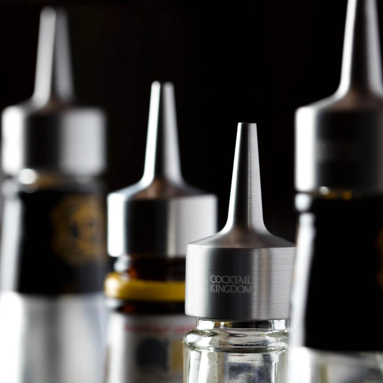 Close-up of cocktail bitters bottles with a dark background.